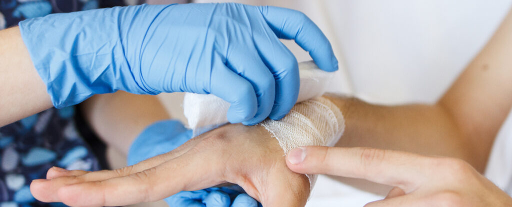 nurse adds a bandage on a hand to a sick patient at home