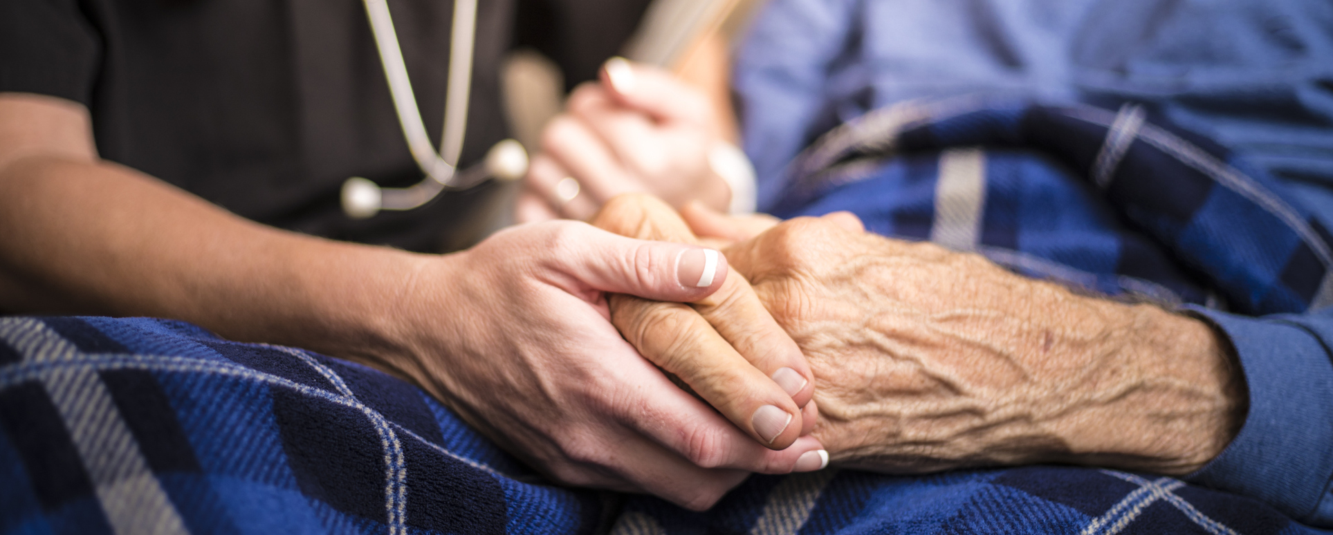 Hospice Nurse visiting an elderly male patient holding their hand