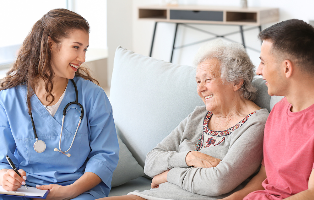 Nurse visiting senior woman at home with family