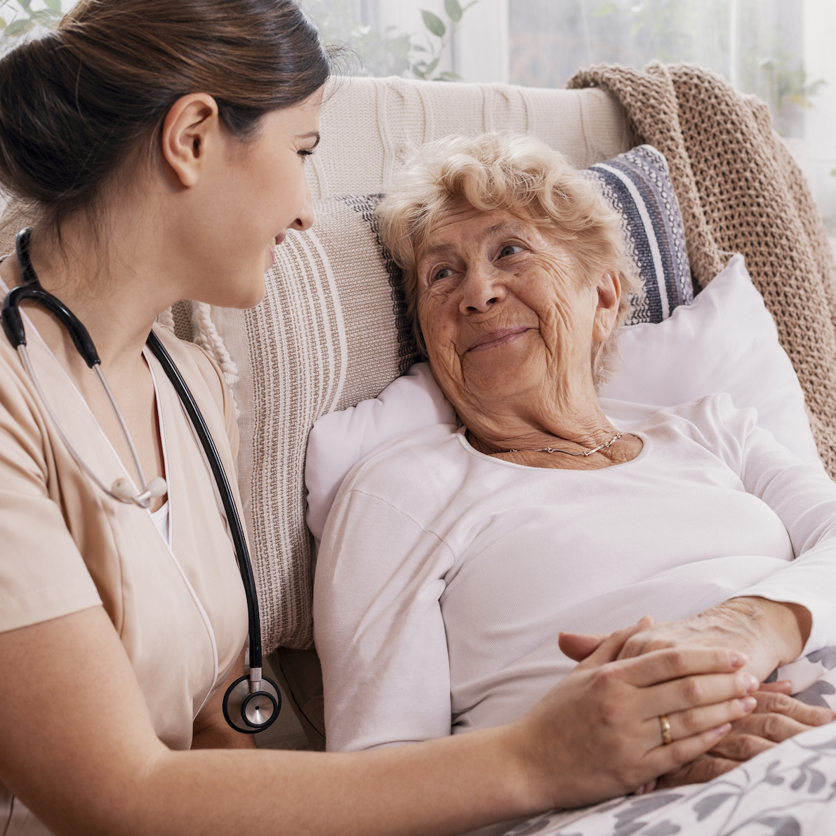 Senior woman lying in bed with nurse